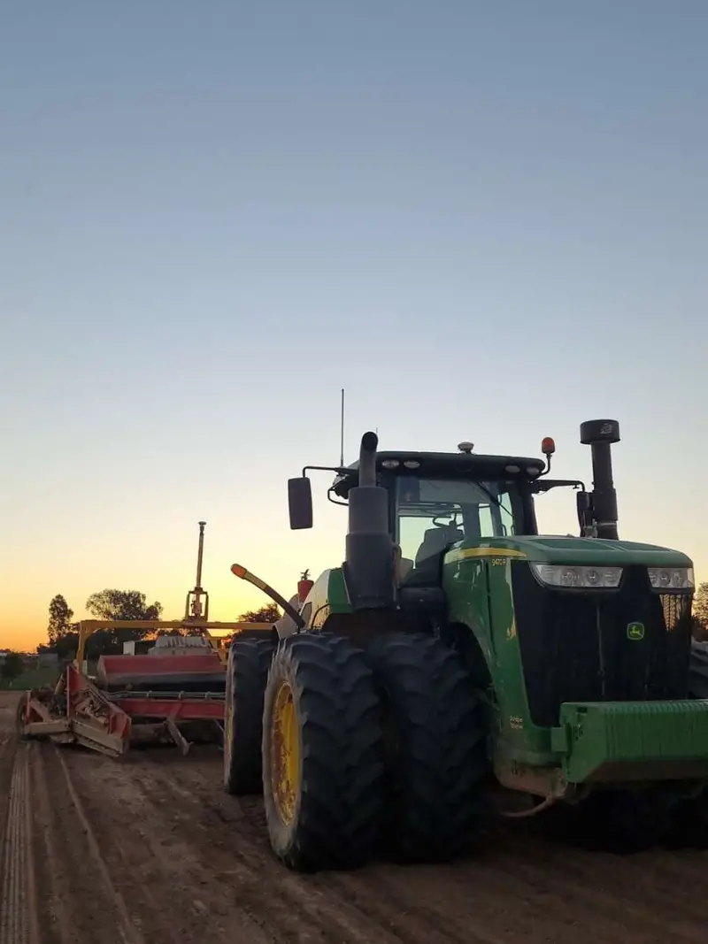 John Deere tractor and landforming equipment at sunset
