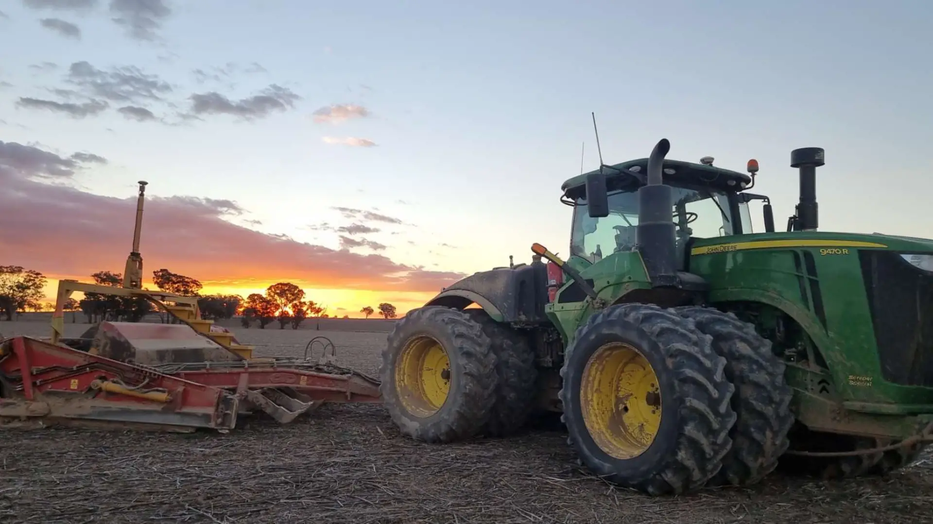 John Deere tractor and landforming equipment at sunset