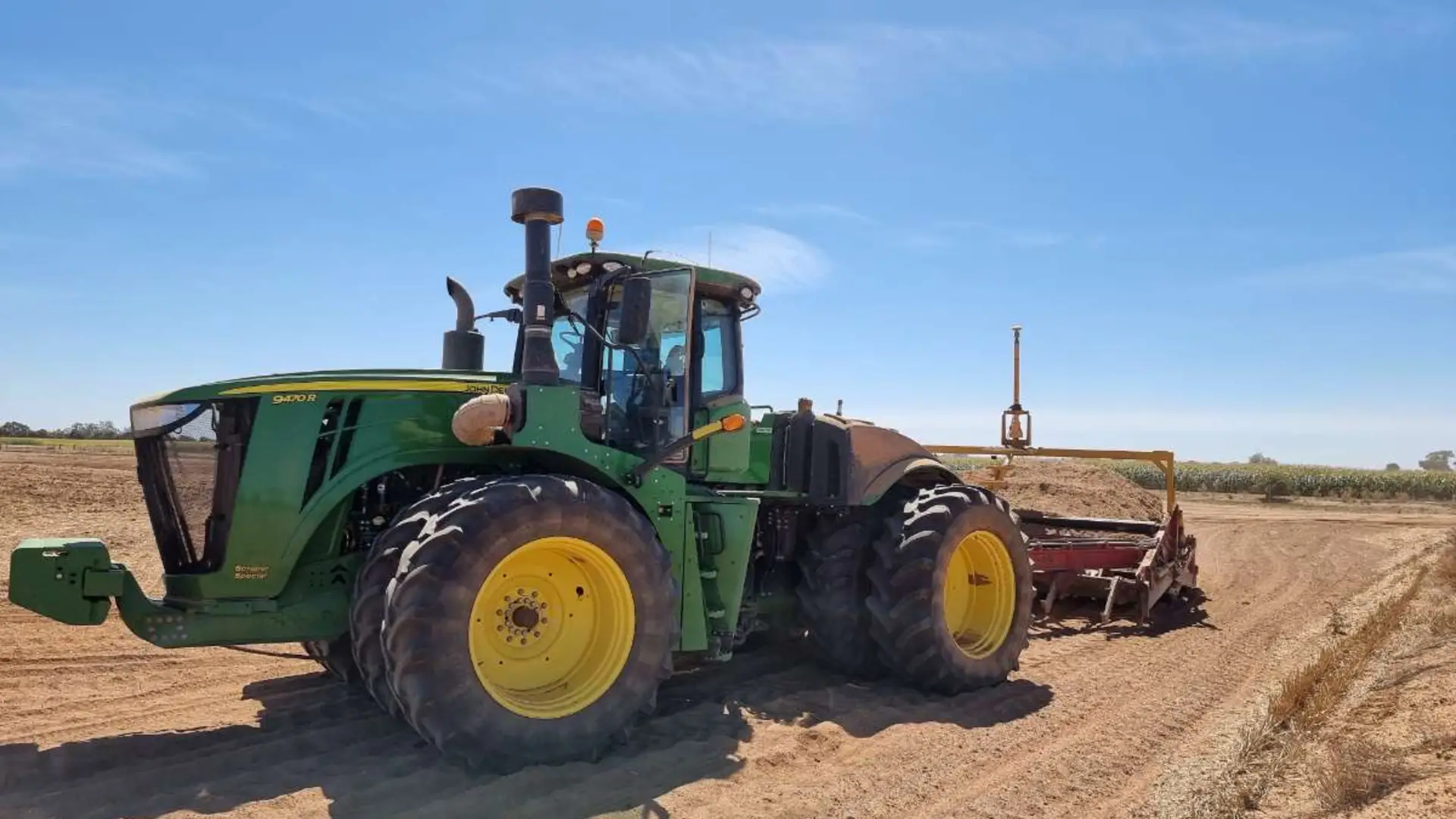 John Deere tractor with landforming scraper and GPS mast